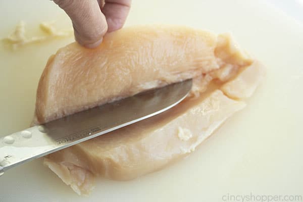 chef’s knife cutting raw chicken breast