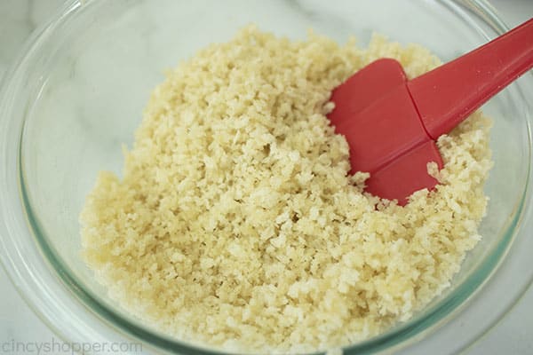 red spatula stirring a bowl of breadcrumb mixture