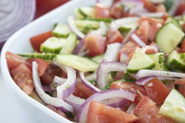 chopped vegetables with dressing in a white bowl