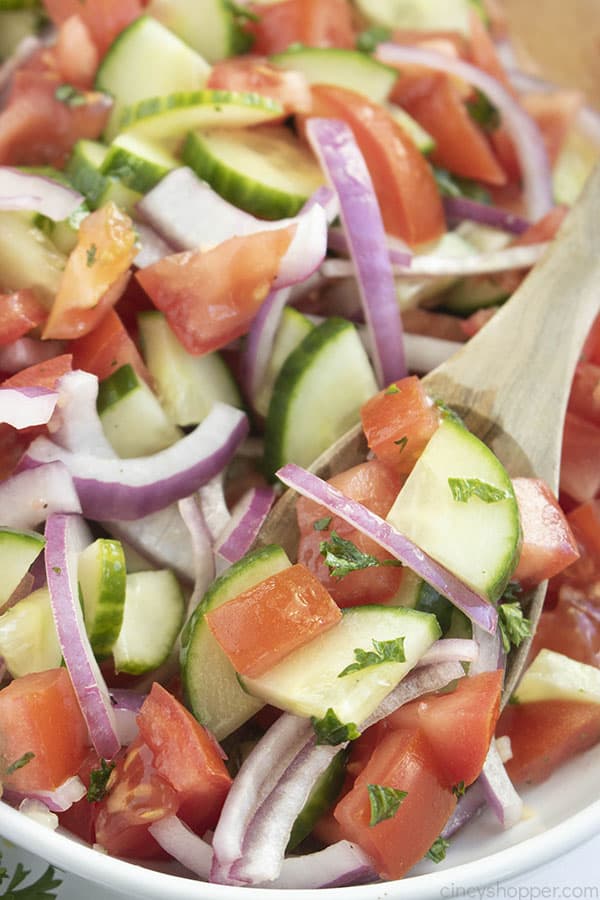 wooden spoon scooping cucumber tomato salad