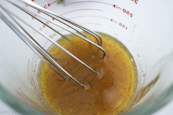 measuring cup with dressing and a metal whisk