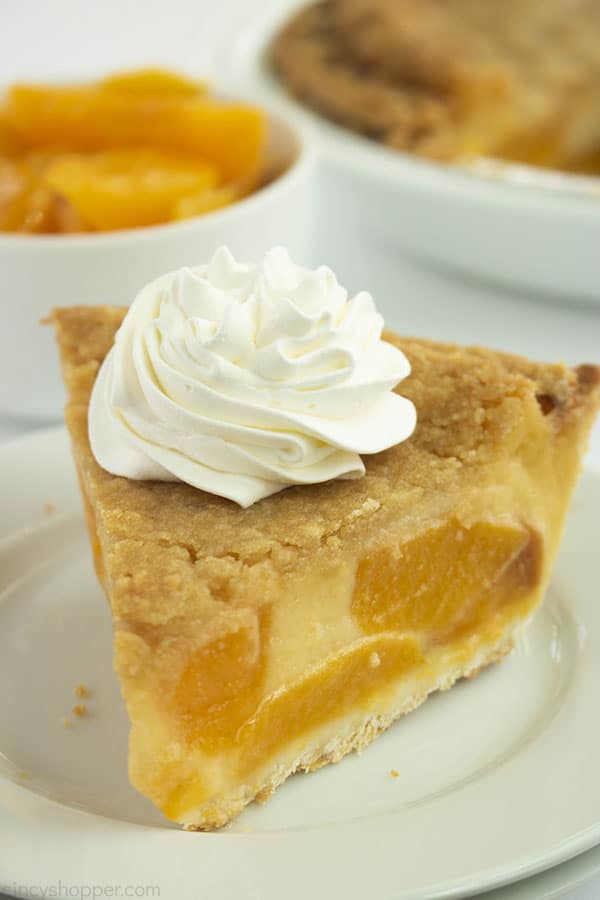 Slice of Custard Peach Pie with whipped topping on a white plate