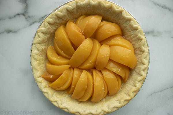 Canned peaches layered in pre-baked pie crust