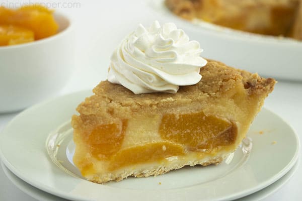 Horizontal image of fresh baked pie with canned peaches on a white plate