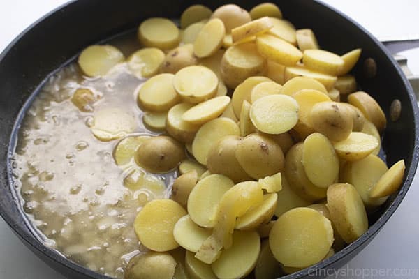 Skillet with cooked onion and boiled potato slices