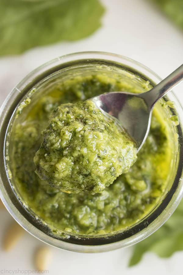 metal spoon scooping pesto out of a jar