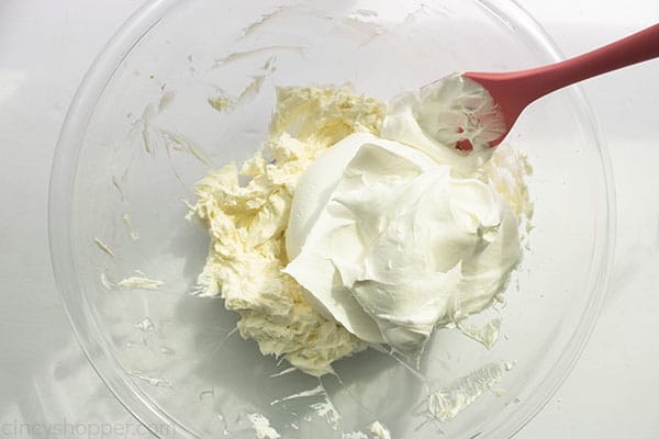 Bowl with cream cheese mixture, whipped topping and spatula. 
