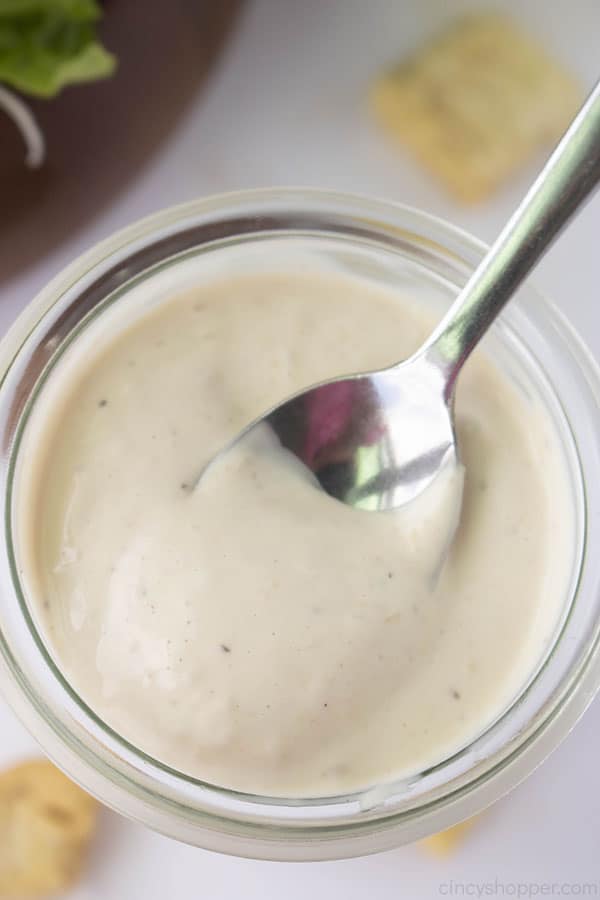 Caesar Dressing in a clear jar with a spoon
