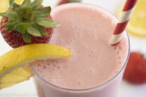 Pink strawberry frosted lemonade in a glass overhead shot with lemon slice and strawberry slice