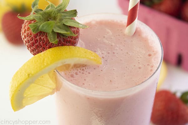 Frosted lemonade strawberry flavored in a clear glass with straw and fruit.