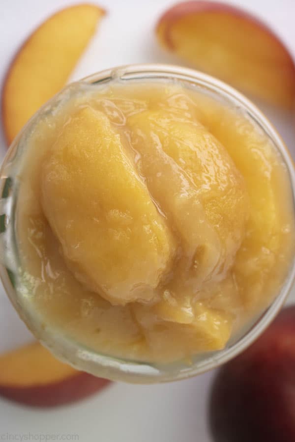 Overhead shot of fresh homemade peach filling in a glass jar on white background