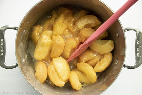 Stainless pan and spatula with cooked peach pie filling