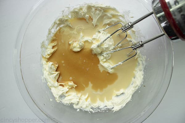 Cream cheese, condensed milk and vanilla in a clear mixing bowl with hand mixer