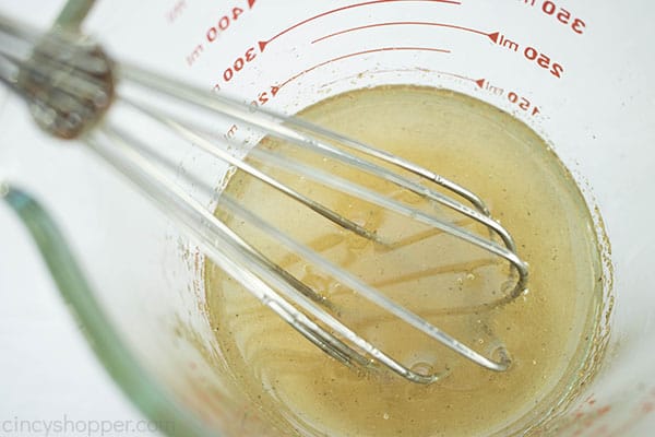 Metal whisk in a measuring cup with dressing