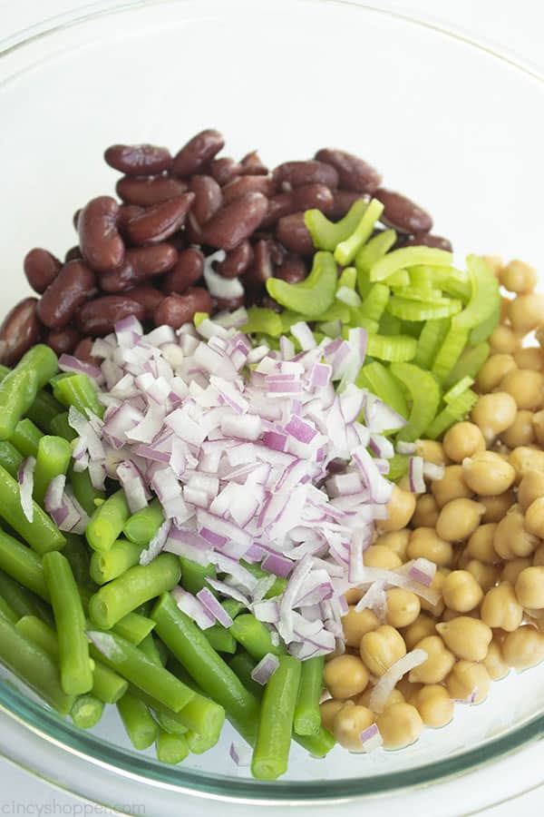 Clear bowl with kidney beans, green beans, chickpeas, celery, and red onion