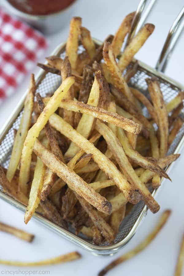 Air Fryer French Fries in a basket with white background with ketchup and a red and white checkered napkin