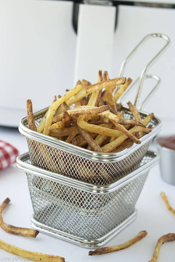 Homemade French Fries in a stainless basket with air fryer in background