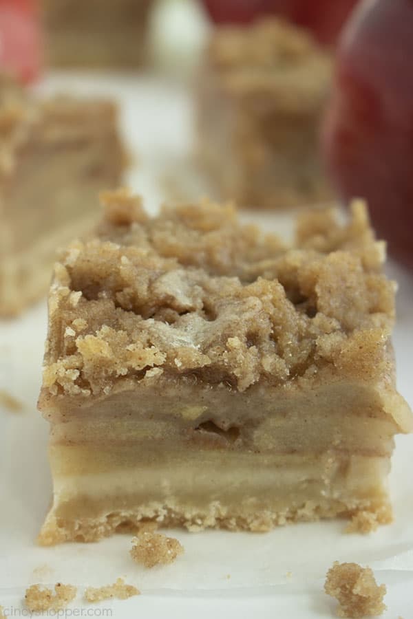 apple crisp bar with crumbs on white paper with apples in the background 