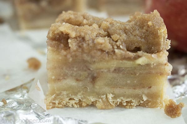 finished apple crisp on foil and white paper with an apple crisp crumb on the right side 