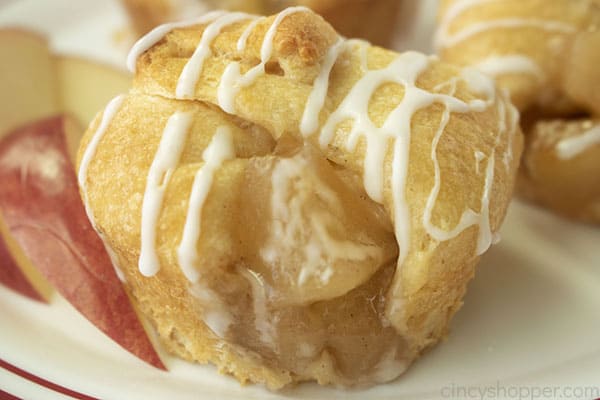 Icing drizzled Apple Crescent pie bites on a white plate.