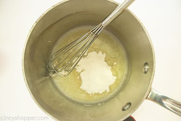 Overhead shot of the cheese mixture ingredients in a medium saucepan with a sliver whisk 