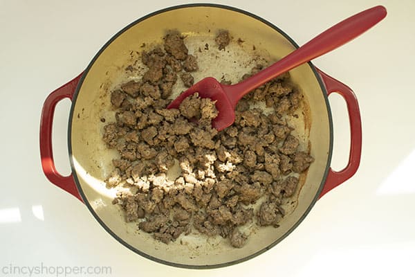 Overhead image of the cooked meat in a red cast iron skillet with a red spatula 