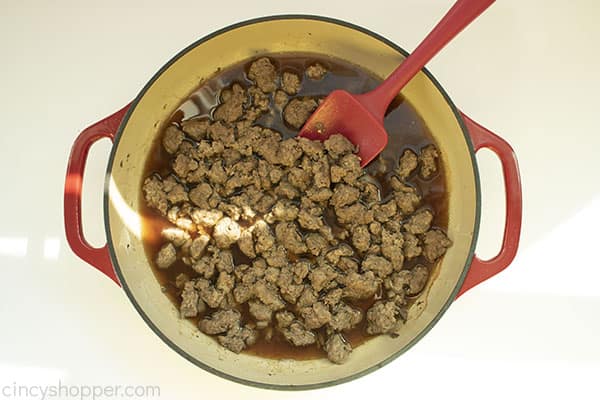 Overhead shot of the Hamburger Helper meat with a Beef Bouillon mixture in a red cast iron skillet with a red spatula 