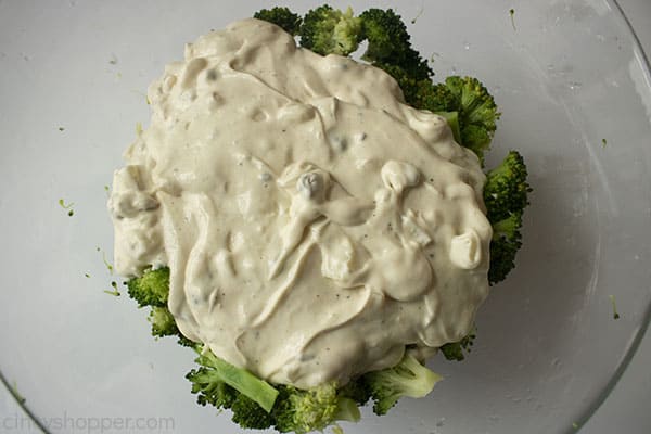 Wet mixture on top of broccoli in a clear bowl 