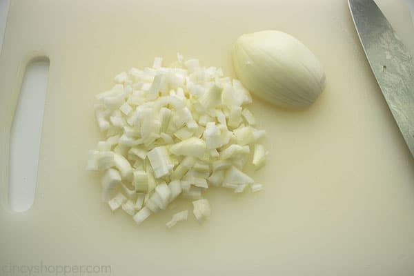 Diced onion on a white cutting board with a knife off to the side