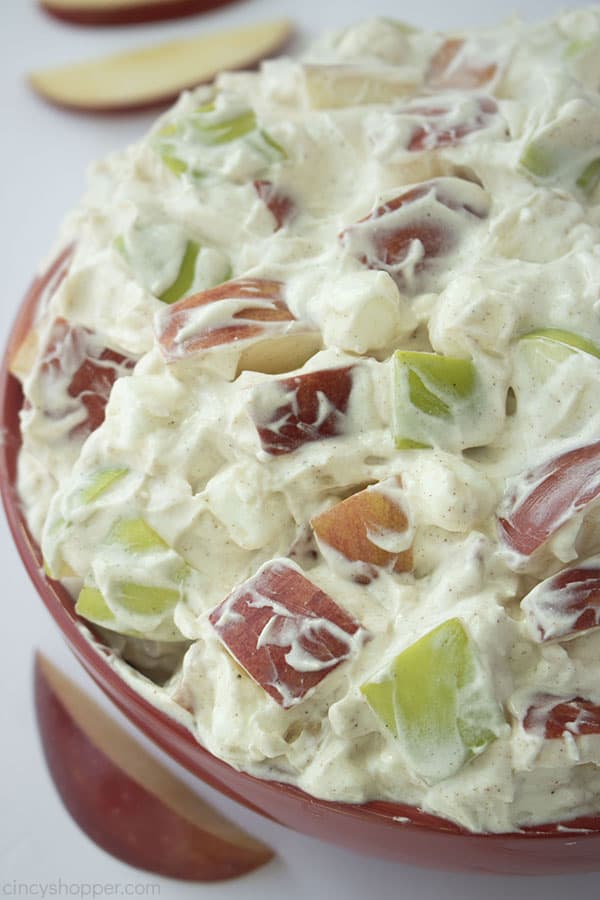 Creamy Apple Salad in a large red bowl with sliced apples in the background 