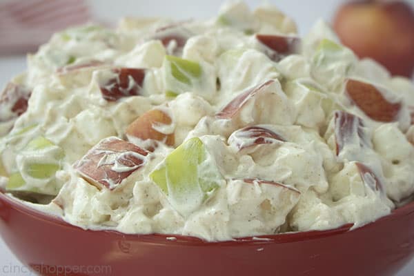 Close up shot of the Creamy Apple Salad in a large red bow a red striped towel and a red apple in the background 