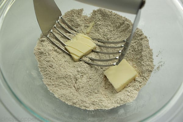 Clear bowl with crumb topping including butter and pastry cutter