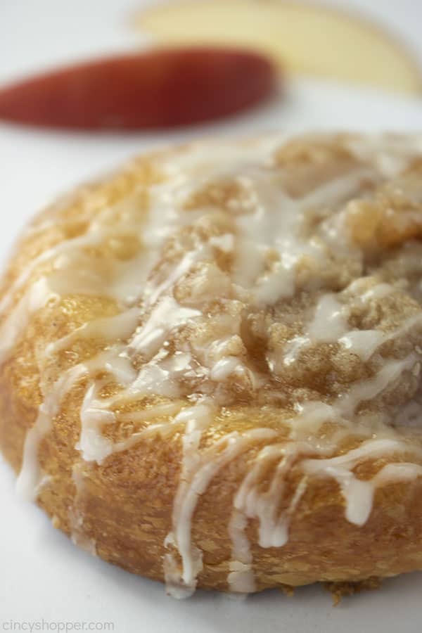 Closeup of the side of crumb topped apple danish with a white background.