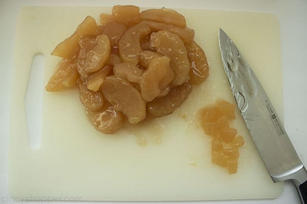 Canned apple filling on a white cutting board with a kitchen knife on side