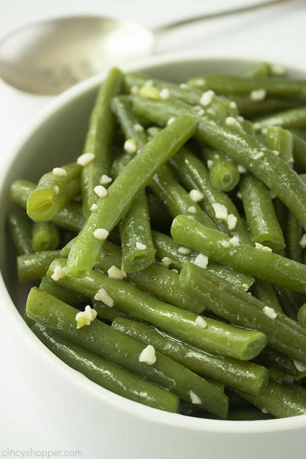 Garlic Green Beans in a white bowl with white background and spoon in th eback