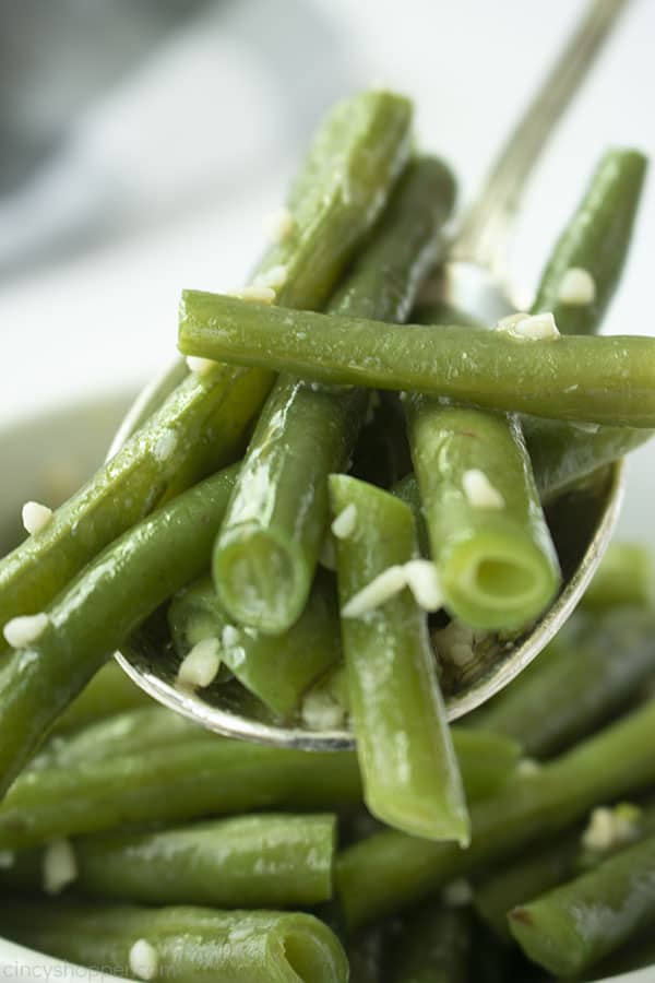 Spoon filled with fresh garlic green beans with butter