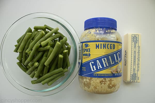 Ingredients to make buttery garlic Green Beans - clear bowl fresh green beans, jar of garlic and stick of butter.