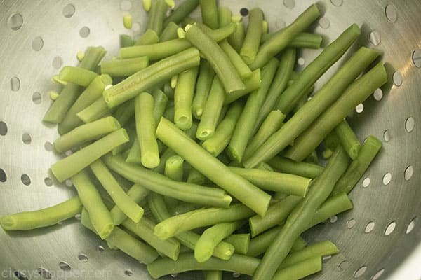 Fresh trimmed green beans in stainless steel colander. 