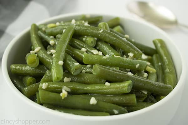 Sideways shot of white bowl filled with fresh garlic butter green beans