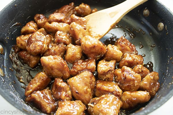 General Tso's Chicken in a black skillet with a wooden spoon.