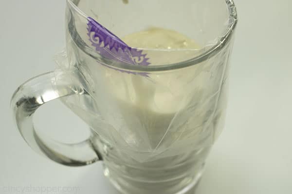 Piping Bag in a tall clear glass with white chocolate on a white background.