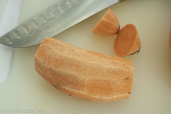 Cut sweet potatoes on a white cutting board with a knife