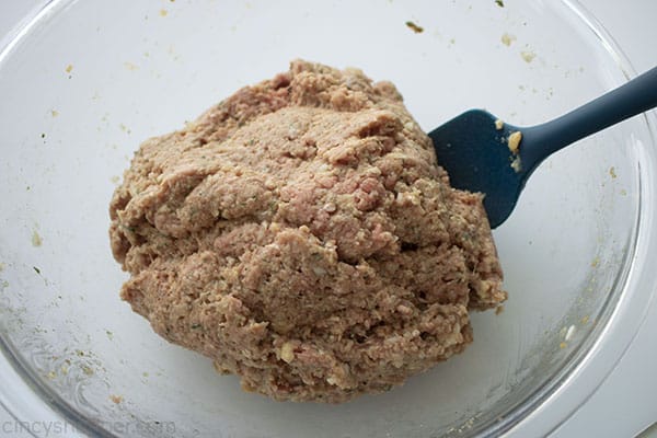 Meatloaf raw ingredients mixed in a clear bowl with a spatula 