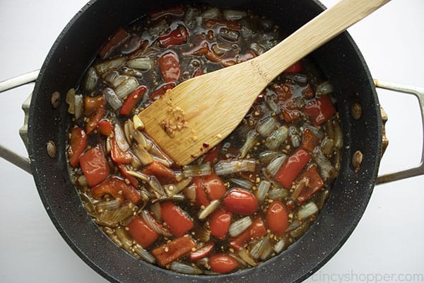 Image of all the ingredients added, minus the Mongolian Beef all cooking in a large black skillet with a wooden spatula 