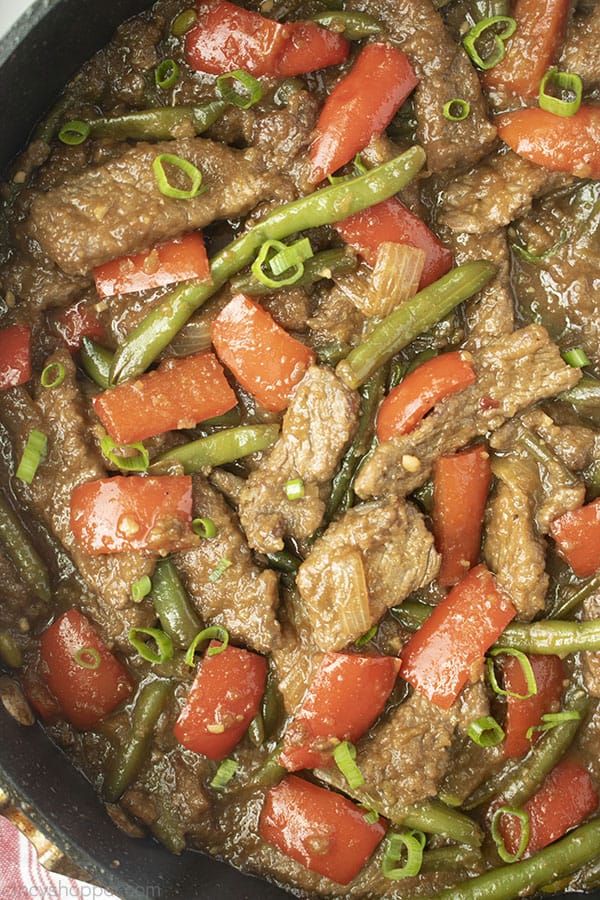 Image of Mongolian Beef with red peppers and greens beans in a black skillet 