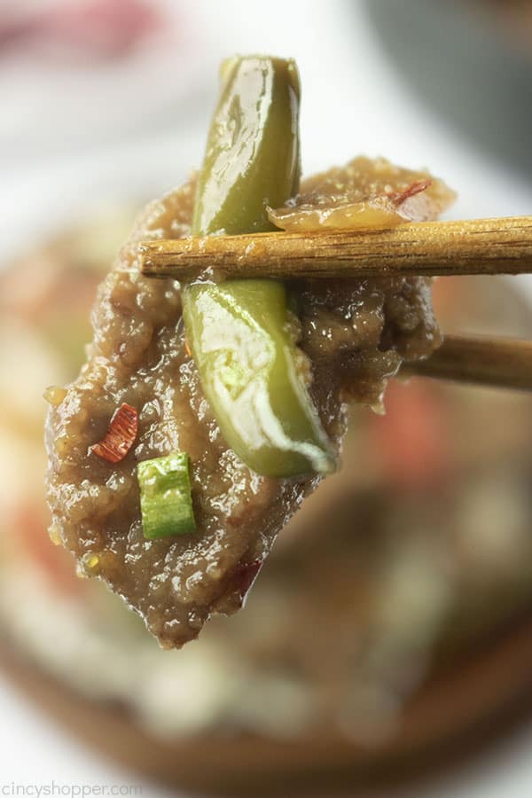 Mongolian Beef close up shot being held with brown chopsticks 