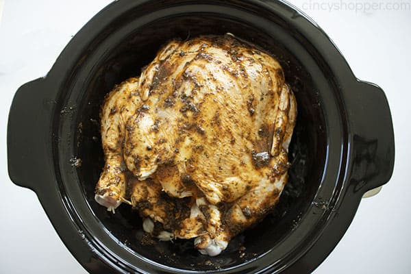 Seasonings rubbed on Rotisserie Chicken in a black crock with a white background