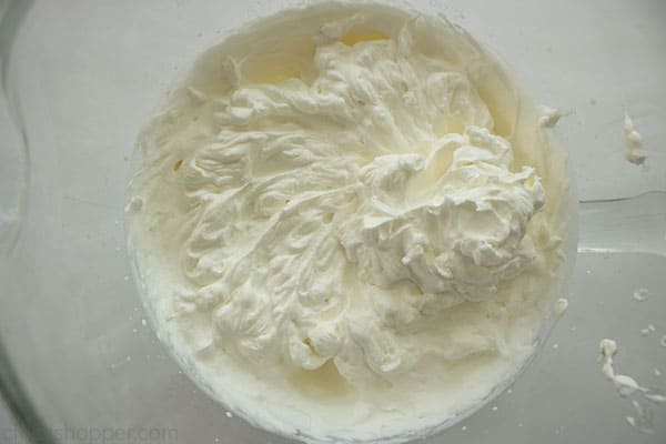 stiff peaks are formed with whipped topping, powered sugar, and vanilla in a large mixing bowl 