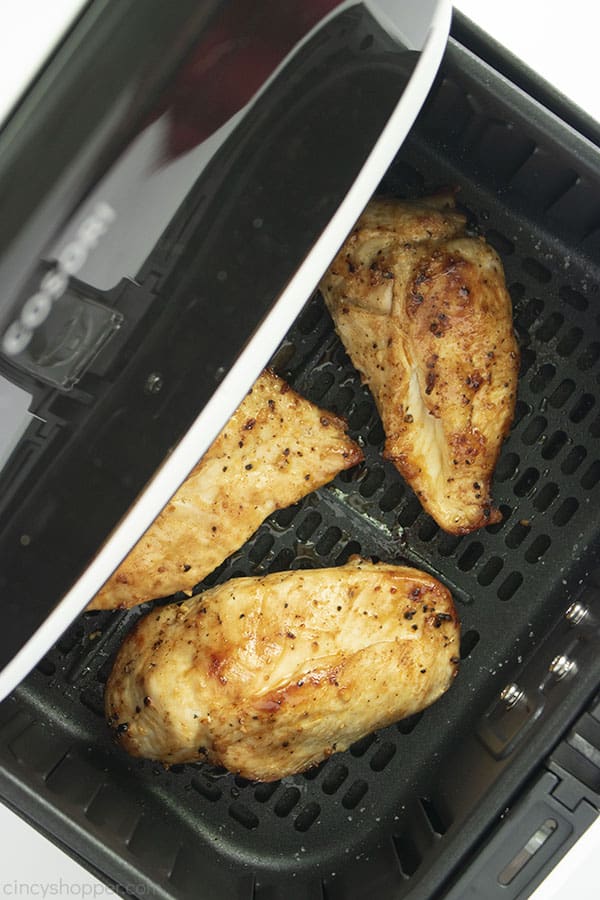 Three cooked crispy chicken breasts in a white air fryer.