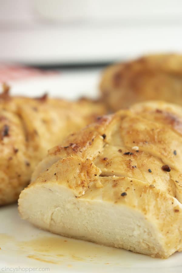 Closeup of juicy air fryer chicken breasts with air fryer in background